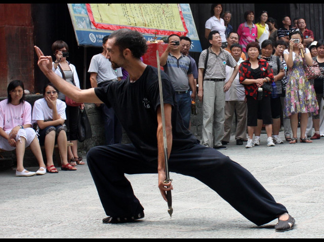 cercle de toursite chinois autour de Mathieu qui enchaine une forme traditionelle de Wudang à l'épée.